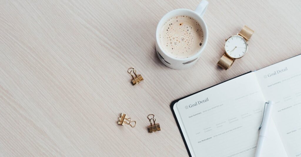 A minimalist desk arrangement featuring a coffee cup, notebook, pen, and wristwatch.